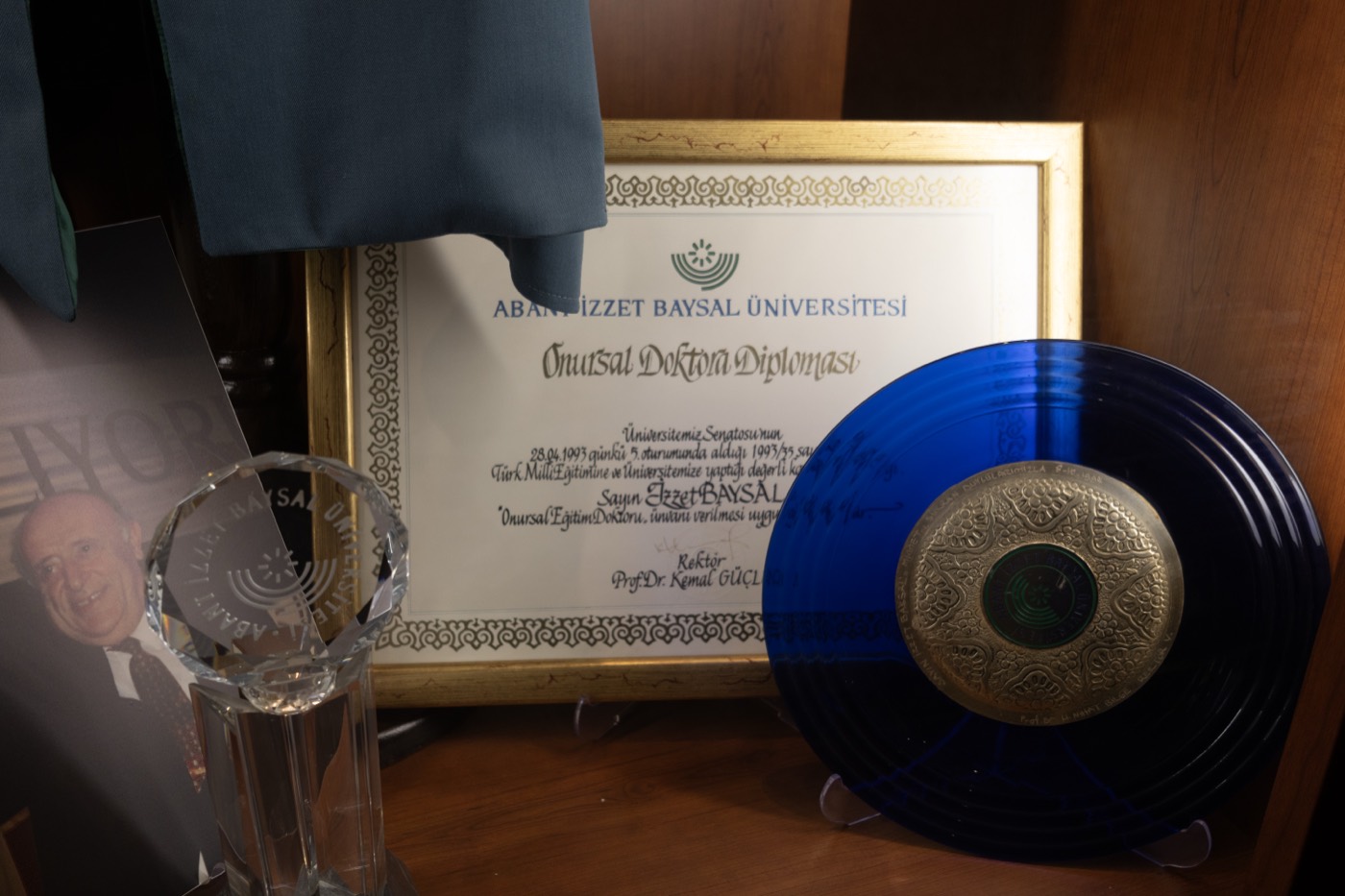 Altın çerçeveli onursal doktora diploması ve yanındaki mavi tabak