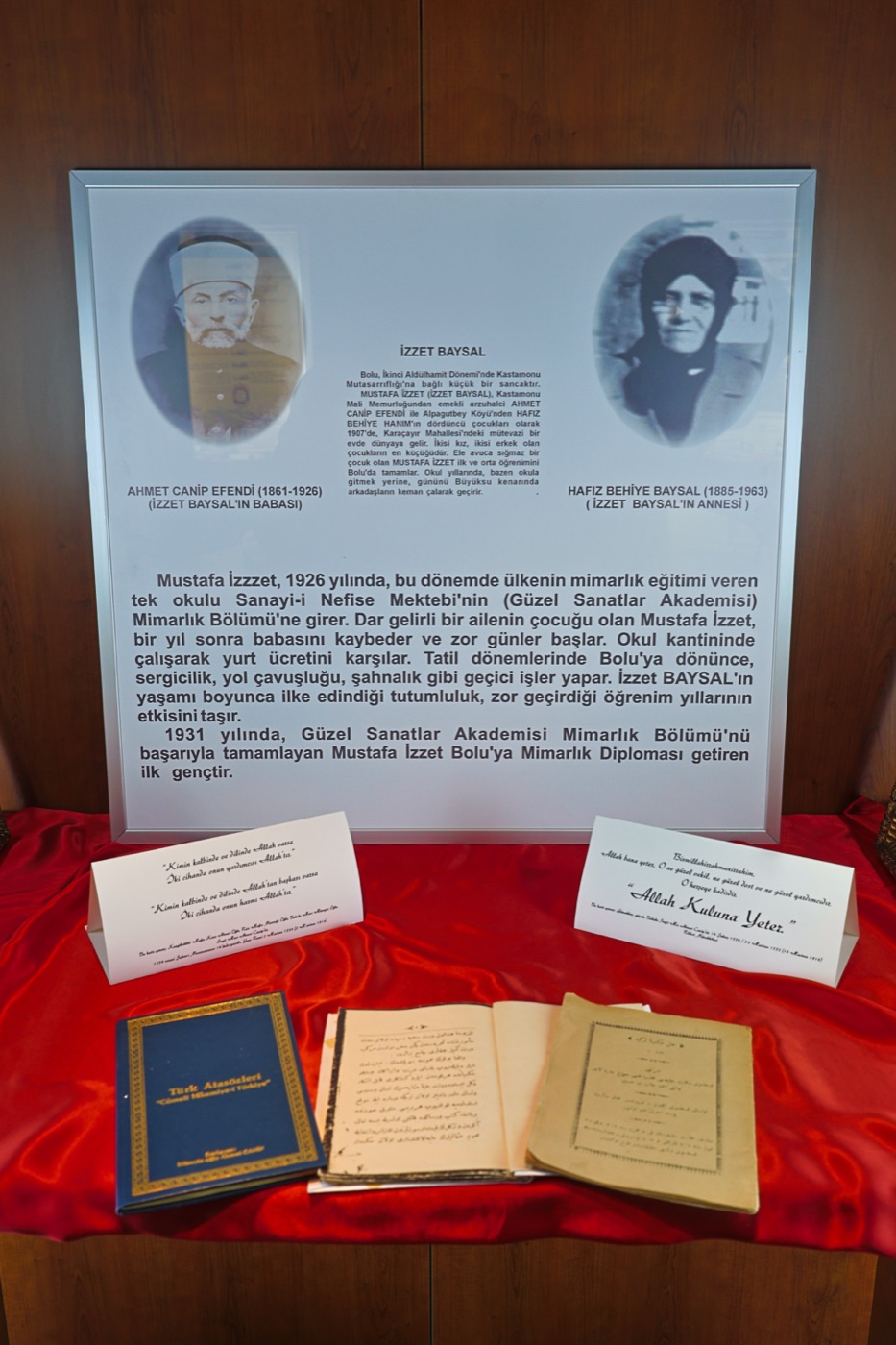 Vitrindeki aile ve öğrenim levhası, önünde el yazması defterler