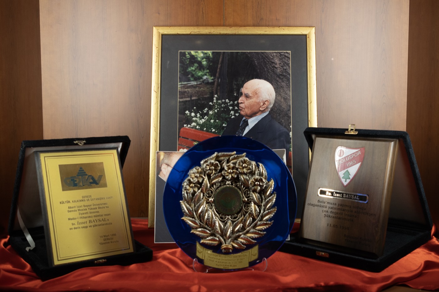 Alt rafta çerçeveli portre, iki plaket ve mavi tabak içinde defne çelengi